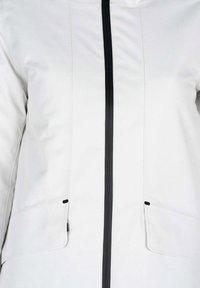 Giacca bianca leggera con zip frontale nera, dotata di due tasche laterali e dettagli in nero a contrasto sulla zip e sui bordi delle tasche.