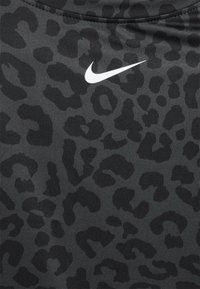 Tecido atlético preto com um padrão de leopardo subtil. Apresenta um logótipo da Nike branco no canto superior esquerdo. Textura suave, design ajustado.