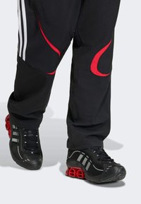 Melnas sporta kurpes ar sarkaniem akcentiem un izcilu zoles dizainu. Aprīkotas ar šņorēm un pelēkām svītrām sānos. Valkātas ar melniem biksēm.