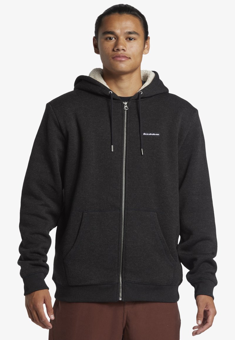 Felpa nera con zip e interno foderato caldo e texturizzato, tasche frontali, cappuccio regolabile con coulisse e un piccolo logo sul petto.