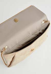 Sac à main en microfibre beige avec une fermeture magnétique dorée et un intérieur en satin lisse. L'intérieur comprend plusieurs poches.