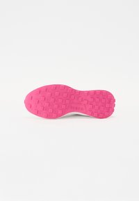 Semelle d'une sneaker, rose avec une surface texturée présentant des indentations carrées, estampillée "Guess" près de la zone du talon.
