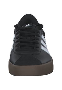 Black athletic shoes with white stripes, made from leather and textile, featuring a round toe, lace-up front, and a brown rubber sole.