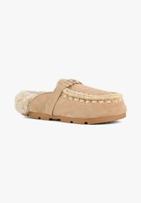 Mule beige in suede slip-on con rifinitura intrecciata, dettaglio fibbia dorata e morbida fodera in shearling visibile al tallone.