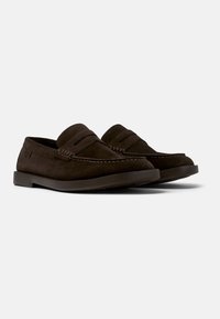 Bruine suède loafers met een platte, donkere loopzool. Heeft een gestikte voorkant en een gladde bovenkant met een losse kraag.