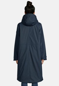 Marineblauwe waterdichte lange jas met een grote kap, naadloos ontwerp en lange mouwen. Heeft een getailleerde taille en subtiele stikseldetails.