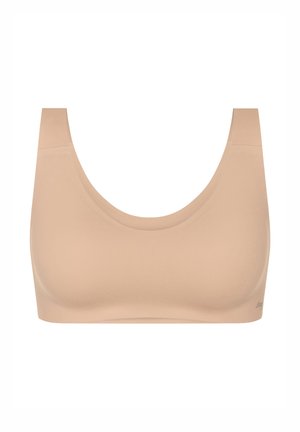Beżowy bezszwowy biustonosz sportowy z szerokimi ramiączkami i głębokim dekoltem, zaprojektowany dla komfortu i wsparcia.