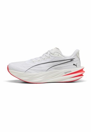 Witte sportschoen met dikke gevormde zool, rode accenten op de buitenzool en zwart Puma-logo op de mesh bovenkant en hielgedeelte.