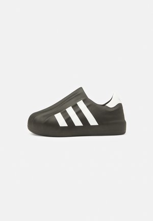 Schwarzer Slip-On-Schuh mit weißem Drei-Streifen-Design und weißem Fersenriemen, von der Seite auf einfachem Hintergrund gesehen.