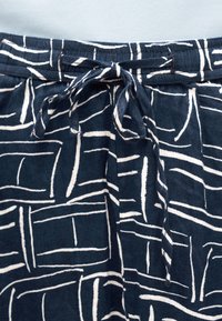 Ύφασμα ναυτικού μπλε με λευκά αφηρημένα ορθογώνια μοτίβα γραμμών, με κορδόνι δεμένο στη μέση.