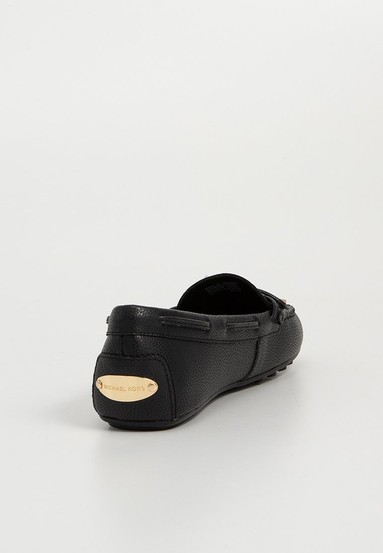 Scarpa slip-on nera in pelle con superficie texturizzata, punta tonda e suola flessibile. Presenta una placca logo in tono oro sul tallone.