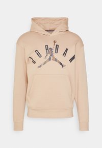 Sudadera con capucha beige que presenta un bolsillo tipo canguro, un logo gráfico "JORDAN" y una silueta icónica saltando en colores abstractos. Material suave, mezcla de algodón.