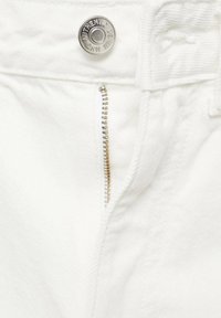 Pantalones de mezclilla blancos con un botón metálico plateado con "AUTHENTIC DENIM" grabado, cremallera con dientes metálicos visibles y tejido texturizado.