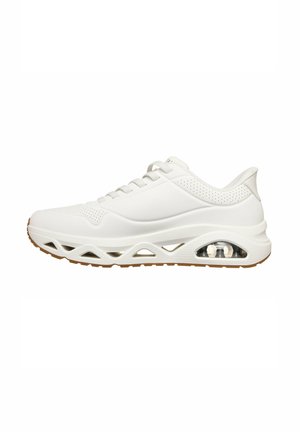 Baskets blanches de sport avec détails perforés, design à lacets, une semelle intermédiaire rembourrée avec motifs découpés, et un coussin d'air visible au talon.