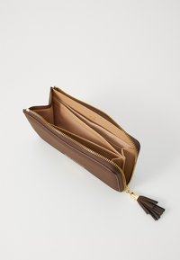 Portafoglio marrone con zip aperto che mostra più scomparti e un interno beige, con un'asola tassel marrone scuro sul tirazip.