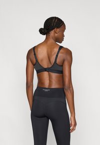 Melnas sporta krūšturis ar regulējamām siksnām un āķa aizdari, kombinēts ar augsta vidukļa melnām legingiem ar logo un smalkām šuvju detaļām.