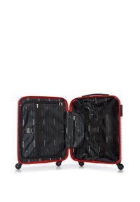 Red hard-shell suitcase opened to reveal a black interior with vertical stripes, zippered pockets, and a cross strap for secure packing.