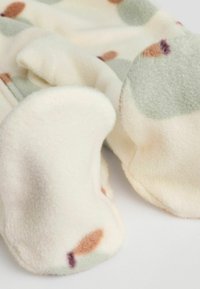 Fleece-tyg i ljus krämfärg med abstrakta gröna, bruna och lila fläckar. Har en mjuk textur och rundade, plyschiga fotdelar.