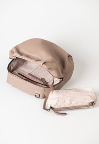 Hellbeige Ledertasche mit runder Oberseite, Reißverschluss und gefüttert Innenteil. Kleinere passende Tasche inklusive, mit einem dezenten Muster und Reißverschluss.