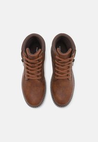 Botas de tobillo de cuero marrón con un acabado texturizado, diseño de cordones y una cremallera lateral. Forro marrón oscuro y detalles de costura en contraste.