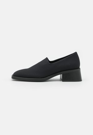 Black slip-on shoe with a smooth fabric upper, pointed toe, and a block heel. The sole is black with a subtle texture detail.