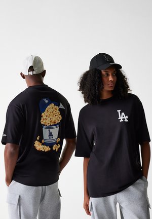 Black t-shirt with graphic of a popcorn bucket on the back and white LA logo on the front. Soft cotton fabric, oversized fit.