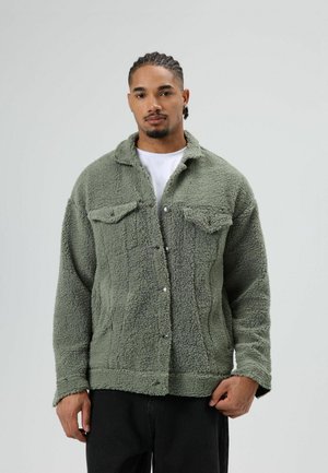 Zachte fleecejas in olijfgroen met drukknoopsluiting, zijzakken en borstzakken. Heeft een shearlingtextuur en een kraag.