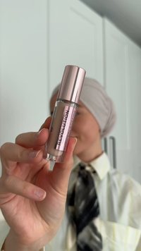 Correcteur liquide transparent dans un tube transparent avec un bouchon en or rose brillant. Le texte sur l'étiquette indique "Revolution Conceal & Define".