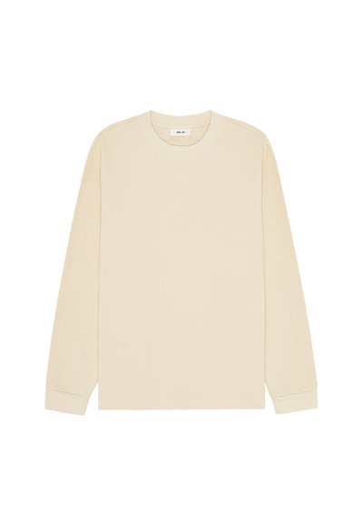 Chemise beige à manches longues en maille gaufrée avec col rond et poignets côtelés, posée à plat sur un fond blanc.