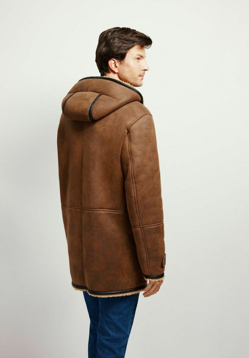 Brauner Ledermantel mit Kapuze, strukturiertem Finish und kontrastierenden schwarzen Nähten. Verfügt über eine Knopfdetail und eine mit Fell gefütterte Kante am unteren Ende.