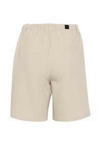 Pantalones cortos beige con cintura elástica, que cuentan con dos bolsillos traseros y una textura suave. El diseño es sencillo y sin adornos.