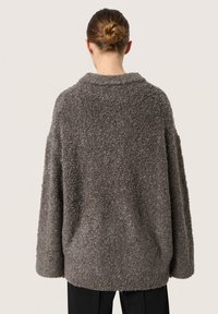 Overdimensioneret grå fleece-sweater med en struktureret overflade, brede ærmer og sjalskrave, med en afslappet pasform og uden synlige lukninger.