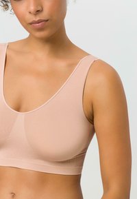 Helles rosa Sport-BH mit breiten Trägern, runder Ausschnitt und glattem, elastischem Stoff. Nahtloses Design verbessert den Komfort und die Passform.