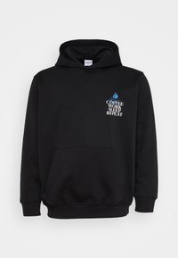 Schwarzer Kapuzenpullover mit einer Fronttasche. Mit weißem und blauem Text: "KAFFEE ARBEITEN SCHLAFEN WIEDERHOLEN" über einer Grafik einer sitzenden Person.