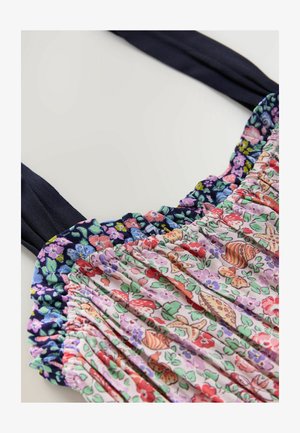 Ziedu raksta kleita ar smocked korseti, kurā ir purpursarkanas, rozā un zaļas krāsas, papildināta ar tumši ziliem siksnām un volānu akcentiem.