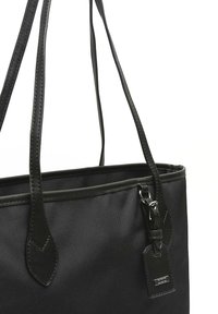 Borsa tote nera con due lunghe tracolle, realizzata in un tessuto resistente, con un accento in pelle liscia e un piccolo tag attaccato.