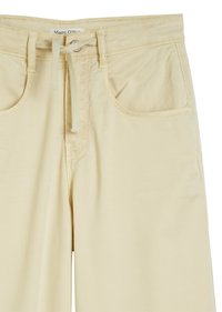 Jasnożółte spodnie wykonane z miękkiego materiału, z elastycznym paskiem wciąganym, dwoma przednimi kieszeniami i prostym wzornictwem bez widocznych wzorów.