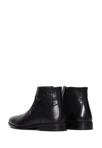 Par de botas de cuero negro hasta el tobillo con hebillas laterales y un patrón de cuadrícula texturizado en las secciones superiores, tacones bajos y cremalleras laterales.