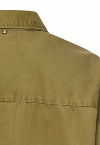 Koszula oliwkowa w kolorze zielonym z kołnierzykiem, wykonana z tkaniny o gładkiej fakturze, z przeszyciem na tylnym karczku oraz małym metalowym detalem powyżej niego.