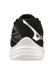 Zapatilla deportiva negra con parte superior de malla texturizada, mediasuela blanca y detalles en plata en el logo. Presenta un talón redondeado y una suela con diseño.