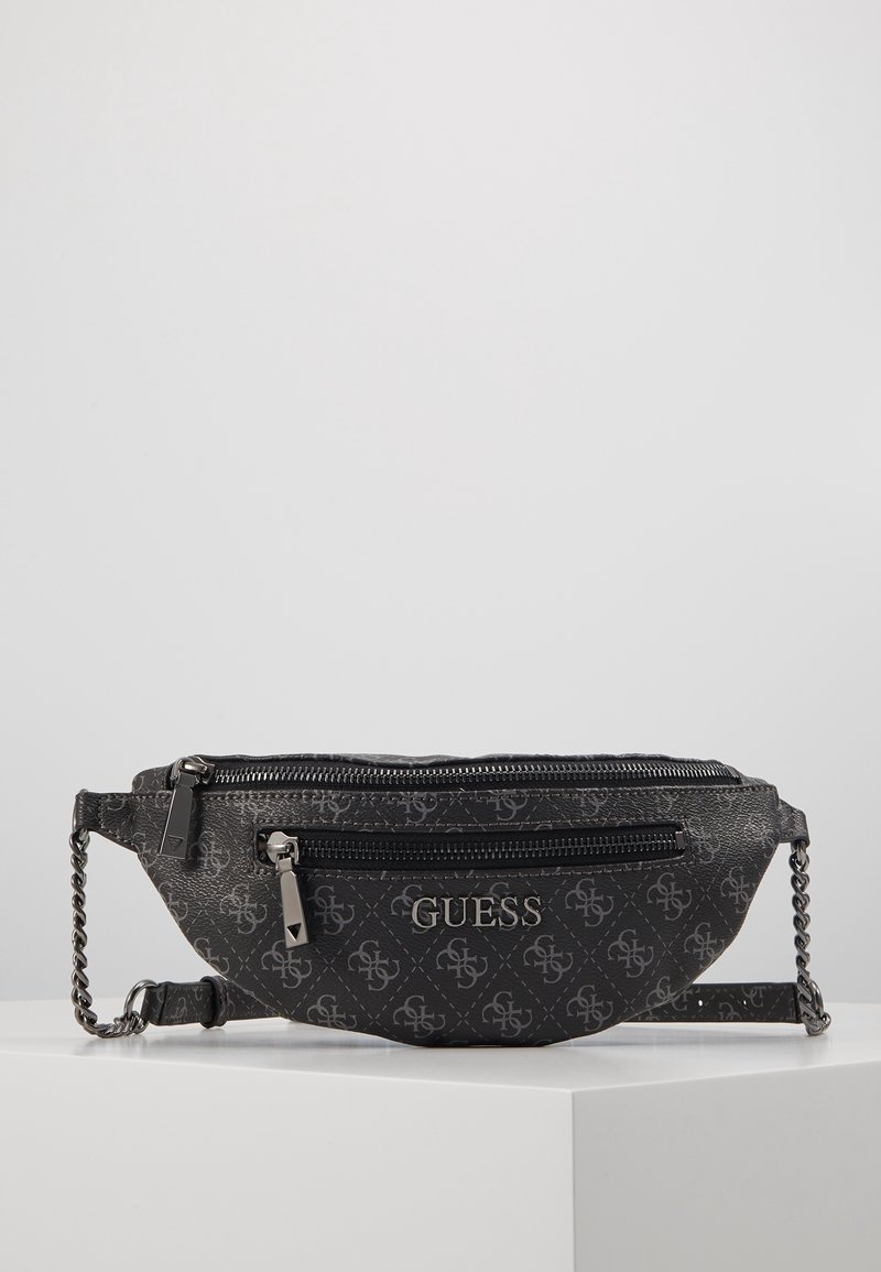 Sac banane noir Guess avec logo argenté, double compartiment zippé, surface à motifs et bandoulière réglable en chaîne sur fond blanc.