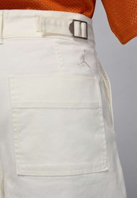 White cargo shorts with a textured fabric, featuring a side pocket and an embroidered logo. Includes a belt with a metal buckle.