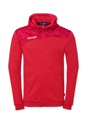 Rød hættejakke med fuld lynlås og geometrisk mønster på skuldrene samt hvidt "Kempa"-logo på øverste venstre bryst.