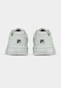 Balts sporta apavi ar mīkstu zolēm, skatīti no aizmugures, katram ir melnbalts "F" logo uz papēža.