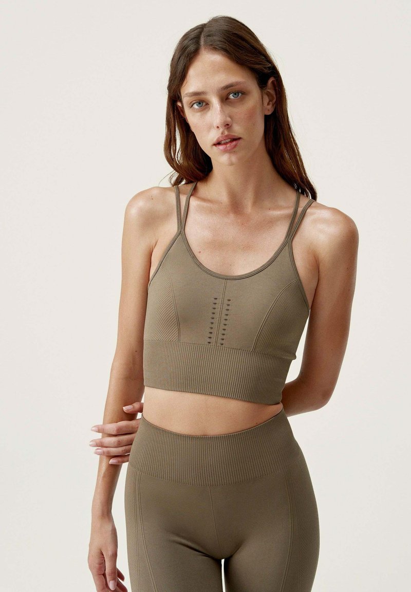 Olijfgroen crop top en high-waisted leggings met ribbelstructuur en naaddetails. Verstelbare banden verbeteren de pasvorm.