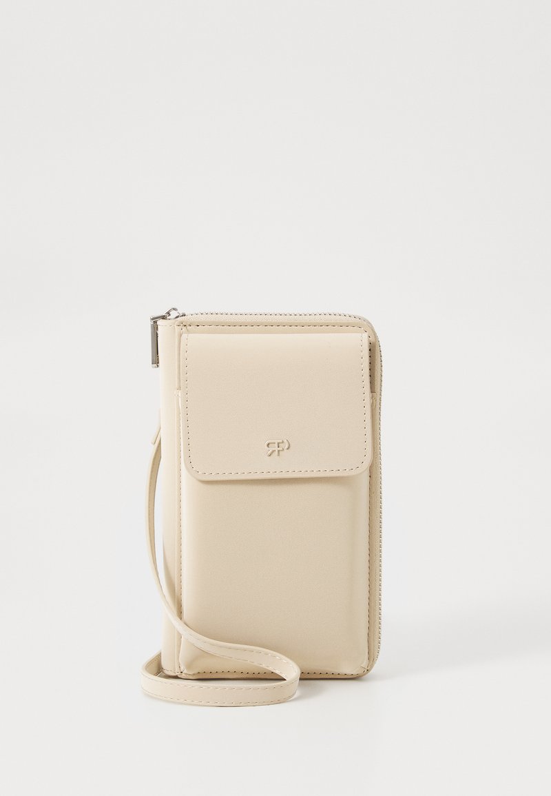 Portefeuille de téléphone en simili cuir beige avec une fermeture à rabat, une sangle ajustable et un logo sur le devant. Texture lisse et design épuré.