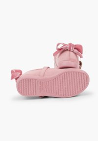 Scarpe rosa in velluto con un fiocco sul lato, punta arrotondata e suola in gomma testurizzata. Presentano una cerniera sul lato e un dettaglio di branding.