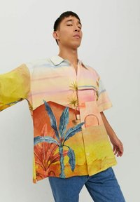 Camicia a maniche corte in colori pastello chiari con stampa di paesaggio tropicale, con foglie di palma e colline, realizzata in tessuto leggero.