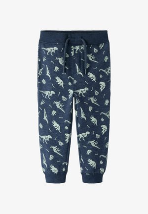 Námořnické tepláky s potiskem dinosaurů a fosilií v světle zelené barvě, s elastickým pasem a šňůrkou, zúžené v kotnících.