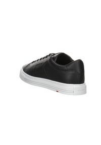 Sneaker en cuir noir avec une forme arrondie, semelle en caoutchouc blanche, couture décorative et logo de la marque sur le côté et à l'arrière.